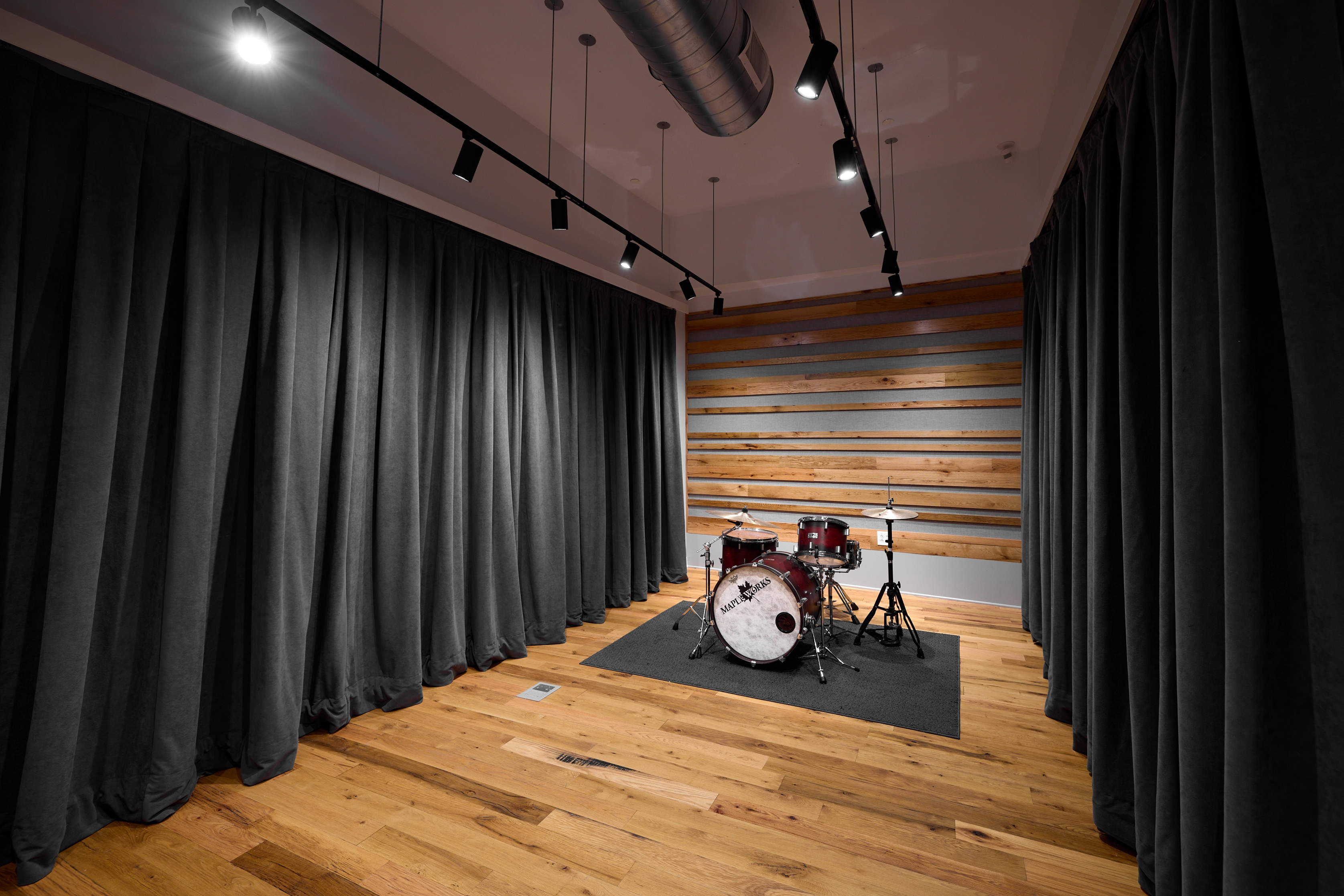 Angled shot of studio B with curtains and a drumset
